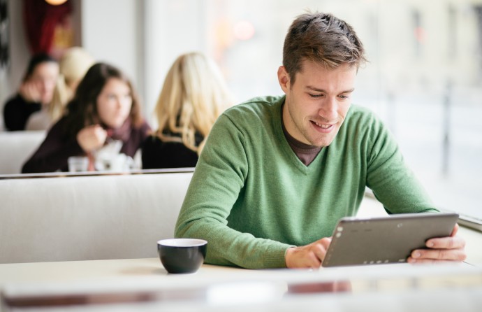 Young man / student using tablet computer in cafe